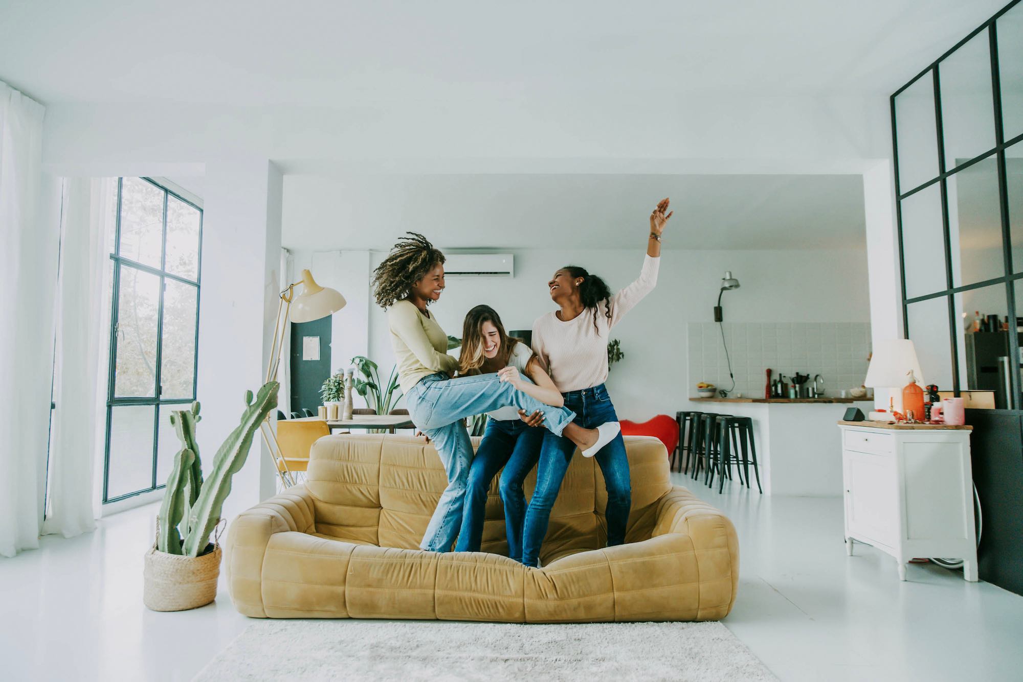 diverse group of female friends enjoying party and laughing together women friends having fun at home dancing on the couch happy lifestyle and friendship concept
